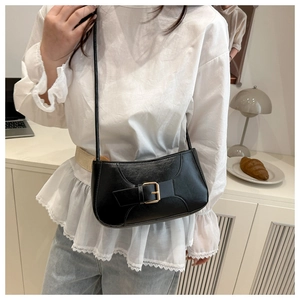 Détail du sac baguette noir en cuir texturé avec une boucle dorée élégante