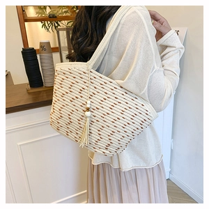 Detail of beige woven tote bag with brown dot pattern and decorative wooden bead tassels