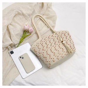 Detail of woven straw tote bag with brown polka dots and bohemian fringe charms