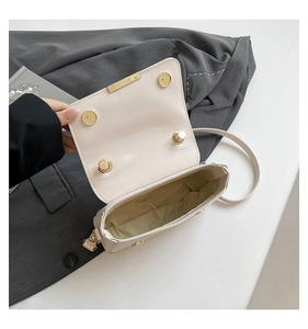 Detail view of cream crossbody box bag interior with gold magnetic closure and fabric lining