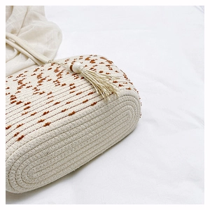 Close-up of woven straw tote bag with brown tufted polka dots and tassel decoration