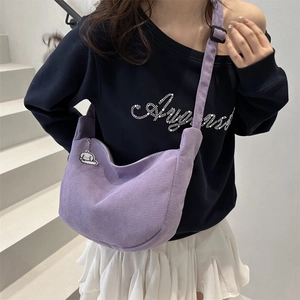 Purple corduroy crescent crossbody bag with cute puppy charm on a model in minimalist setting