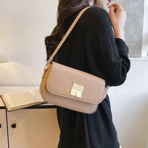 Beige minimalist shoulder bag with gold square buckle shown on model in studio