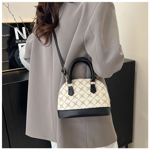 Détail d'un sac à main en forme de coquille avec motif floral et ferrures dorées