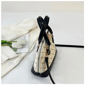 Vue détaillée du sac coquille avec imprimé monogramme, cuir noir et garnitures dorées