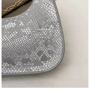 Detailed close-up of silver snakeskin texture and gold metal chain on baguette bag