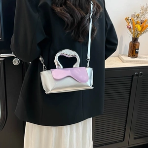 Metallic silver handbag with purple wavy flap and unique silver handle on a table