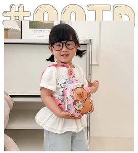Détail du sac bandoulière rose à carreaux avec ours mignon porté par un enfant