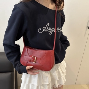 Retro red leather baguette bag with a gold buckle worn as a shoulder underarm bag