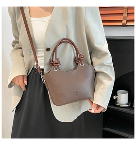 Close-up of a brown leather bucket bag with unique knot handles and adjustable shoulder strap