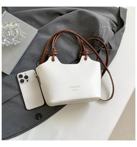 Detail of white two-tone bucket bag with leather strap and fashion logo lettering
