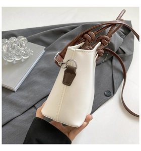 Detail shot of cream PU leather bucket bag with brown knotted straps and silver hardware