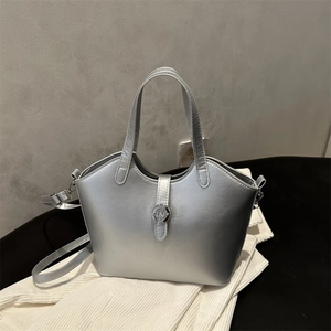 Metallische silberne Eimertasche mit Henkeln und verstellbarem Gurt auf Samtstoff