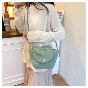 Detailed view of mint green woven bucket bag with large pearl button and spiral flap