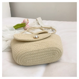 Detailed close-up of handmade woven shoulder bag featuring a decorative pearl clasp