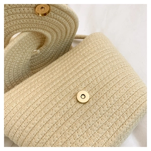 Detail of a woven straw bucket bag showing the golden magnetic metal clasp and texture