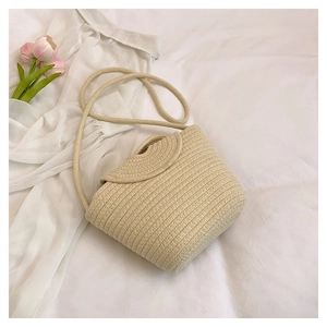 Detail of beige woven straw crossbody bag with pearl flap and soft cotton rope strap