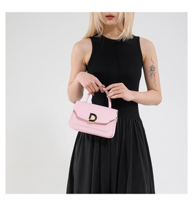 Detail of a pink leather handbag featuring a metallic D-letter clasp and top handle