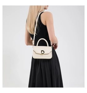 Detail view of cream crossbody bag with gold D-buckle and adjustable strap on model
