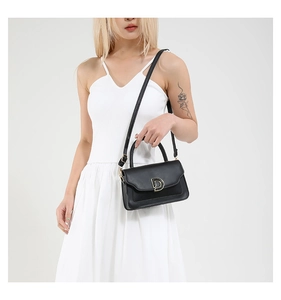 Detailed view of the black leather texture and the golden D-shaped buckle on the crossbody bag