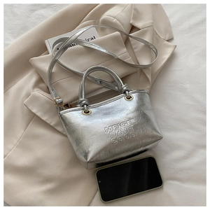 Detail of silver metallic bucket bag with embossed lettering and adjustable strap