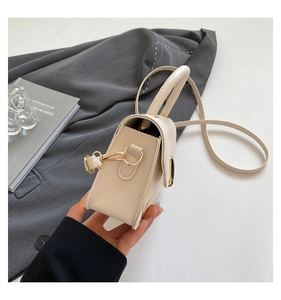 Detail view of the beige crossbody bag's 3D structure and elegant gold hardware accents