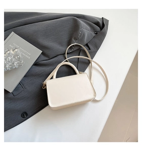 Detail of minimalist cream PU leather crossbody bag with gold metal hooks and handle
