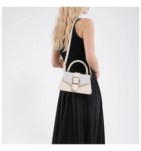 Detailed view of beige handbag with silver sequins and gold buckle on a model in black dress