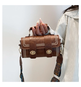 Close-up of brown litchi pattern leather bag with dual twist locks and ethnic strap