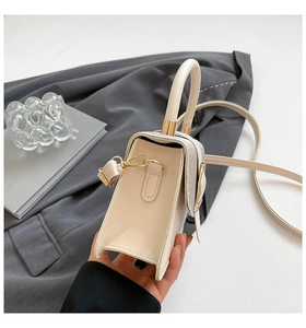 Detail of cream square handbag showing shiny sequin side panels and golden hardware