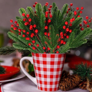Close-up of Christmas PE pine needle branch with red berries in a plaid ceramic mug