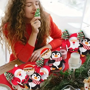 Woman holding festive Christmas lollipop cards featuring Santa, trees, and penguin designs