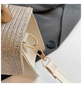 Close-up of cream leather bag with sparkling rhinestones and gold metal hardware link