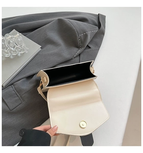 Detail view of cream crossbody bag interior with black lining and magnetic gold clasp