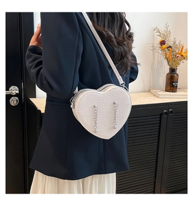 Detail of white heart-shaped crossbody bag with crocodile texture and silver bead chains