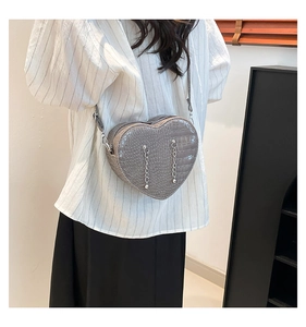 Detail of dark heart-shaped crossbody bag with crocodile pattern and silver chain decor