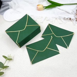 Macro view of premium dark green envelopes with elegant gold foil borders for wedding invitations