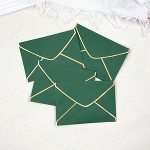 Detail of four dark green envelopes with gold foil borders and V-shaped flaps