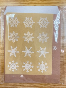 Detail of Christmas snowflake stickers and brown kraft envelopes for gift packaging