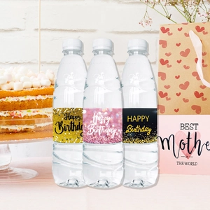 Close-up of glittery Happy Birthday mineral water bottle stickers for party decor