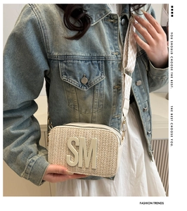 Detail of woven straw crossbody bag with SM logo and decorative geometric jacquard strap
