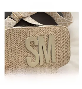 Macro detail of beige woven straw bag featuring SM logo and geometric pattern strap