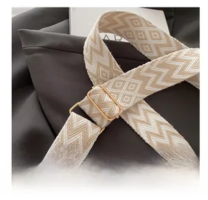 Detail of adjustable metal buckle on beige woven strap for summer crossbody bag
