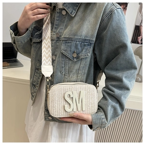 Detail of herringbone weave texture and bohemian jacquard strap on beige camera bag