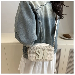 Detail of white woven crossbody camera bag with gold metal buckles and SM letter logo