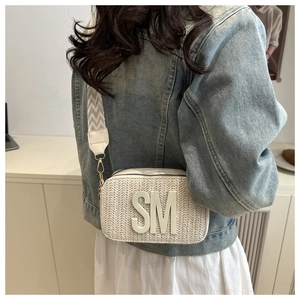 Detail of cream woven crossbody bag featuring large 3D letters and a stylish wide strap