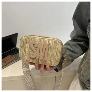 Detail of straw crossbody camera bag with leather SM logo and patterned wide strap