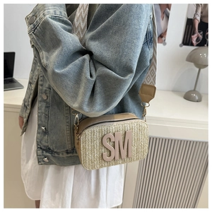 Detail of a beige woven straw crossbody bag with SM patch and wide jacquard strap