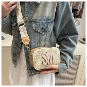 Detail of beige straw camera bag with leather trim and wide bohemian shoulder strap