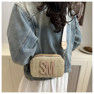 Detail of woven straw crossbody bag with SM logo and white geometric jacquard strap